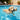 Dog swimming in a pool with a toy in its mouth, surrounded by outdoor furniture and plants.